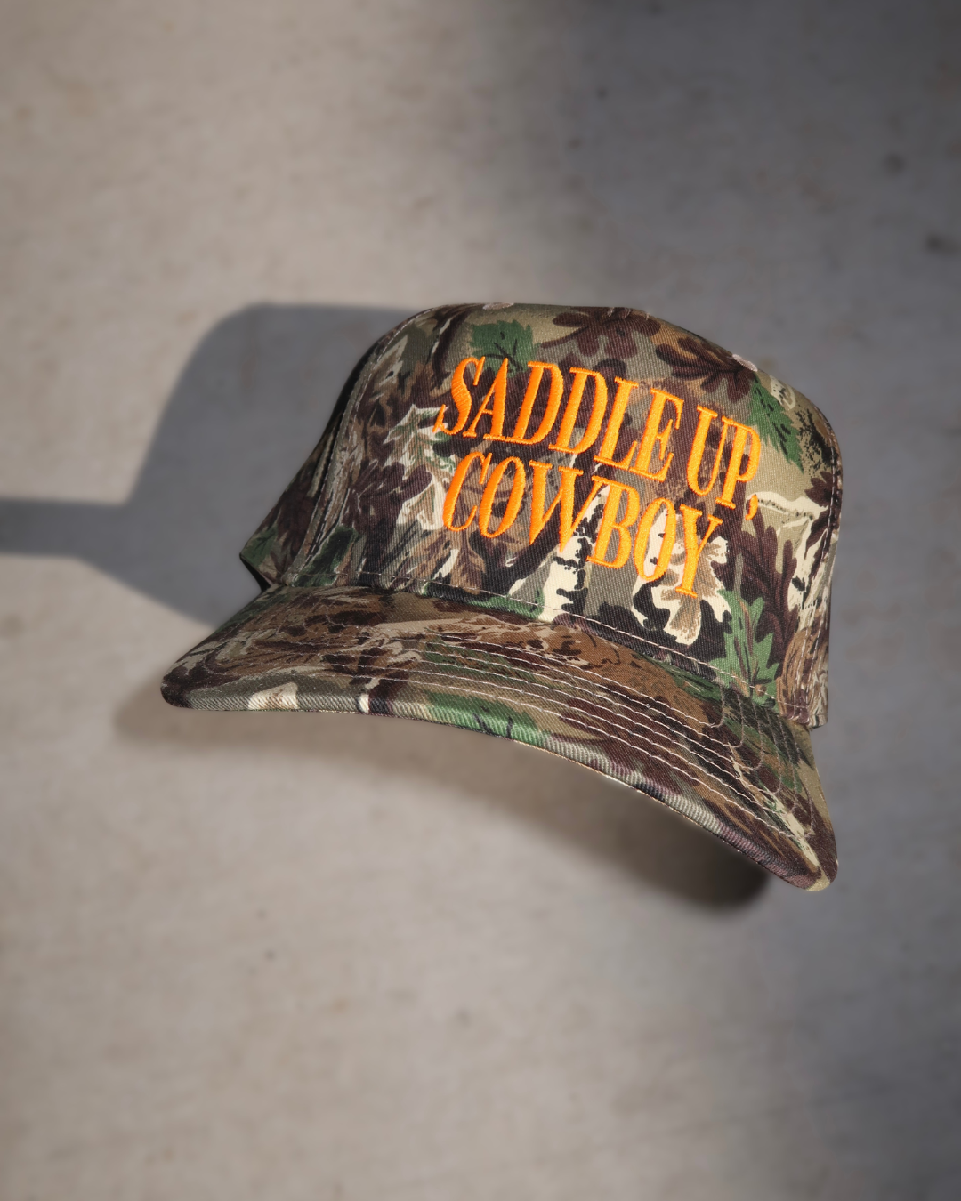 camo trucker hat, hat cowboy snapback, snapback cap country, country western cap, cap woodland hunting, hunting headwear orange, orange embroidered hat, hat rodeo style, style rustic hunting, hunting camouflage baseball, baseball hat outdoor, outdoor ranch accessory, saddle up cowboy
